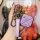 A hand holds a stylish baojun kiwi ev key cover, featuring a sleek purple design with a leather strap and metallic accents, o...
