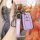 A hand holds a stylish purple toyota key cover, featuring a sleek design with lock and unlock buttons, a branded strap, and a...