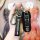 A hand holds a porsche key fob with a leather strap and carabiner, showcasing the iconic porsche emblem and sleek design. per...